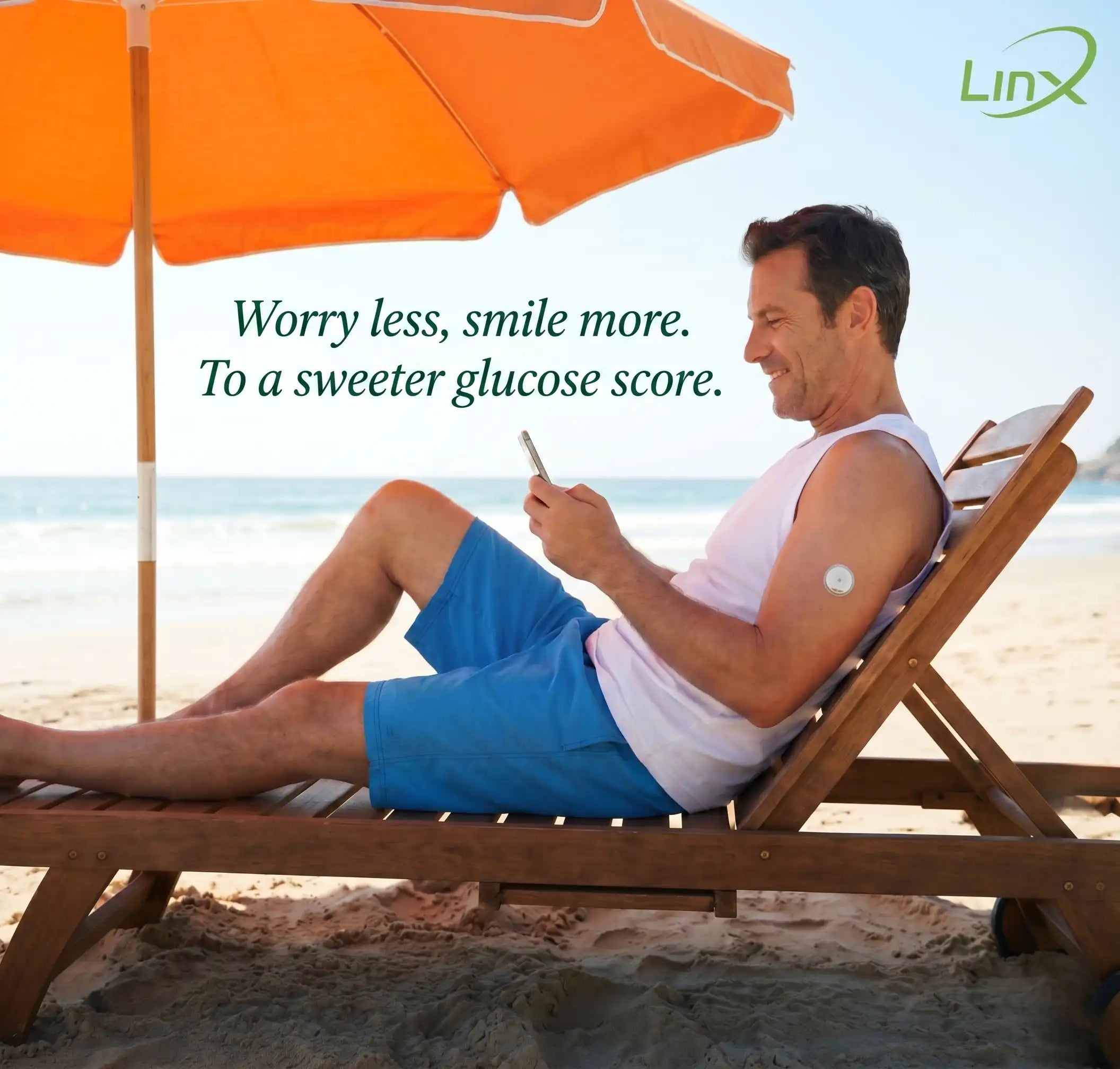Smiling man with arm sensor relaxes on beach chair, checking phone on the beach